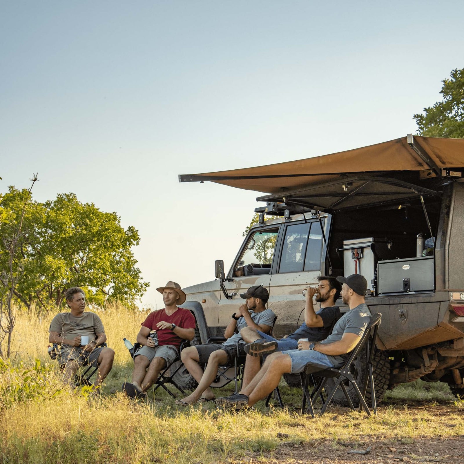 The Bushtech crew at camp beside a canopied Land Cruiser at sunset