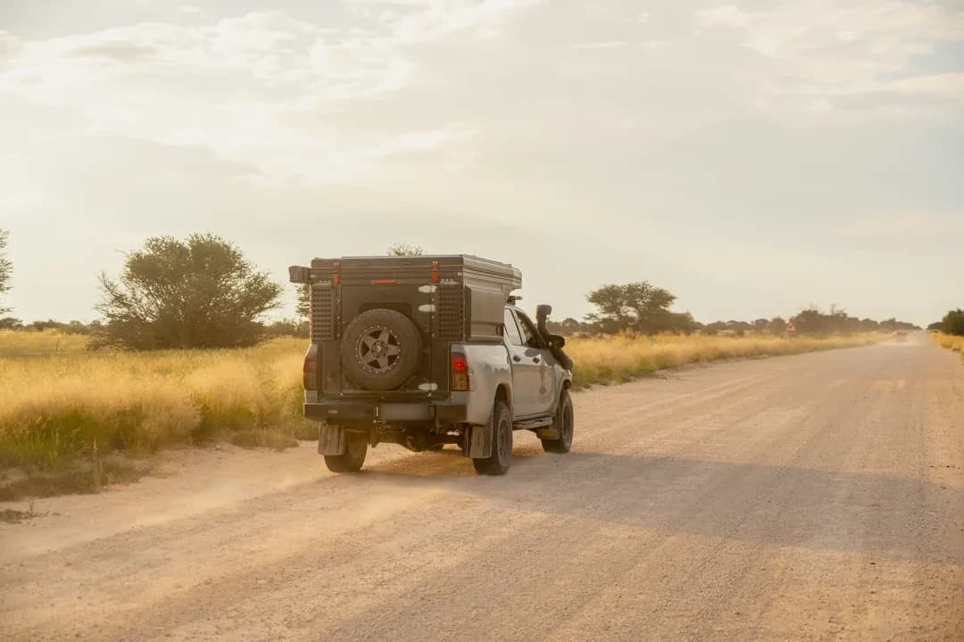 A Hilux with a Bushtech canopy on a sand road